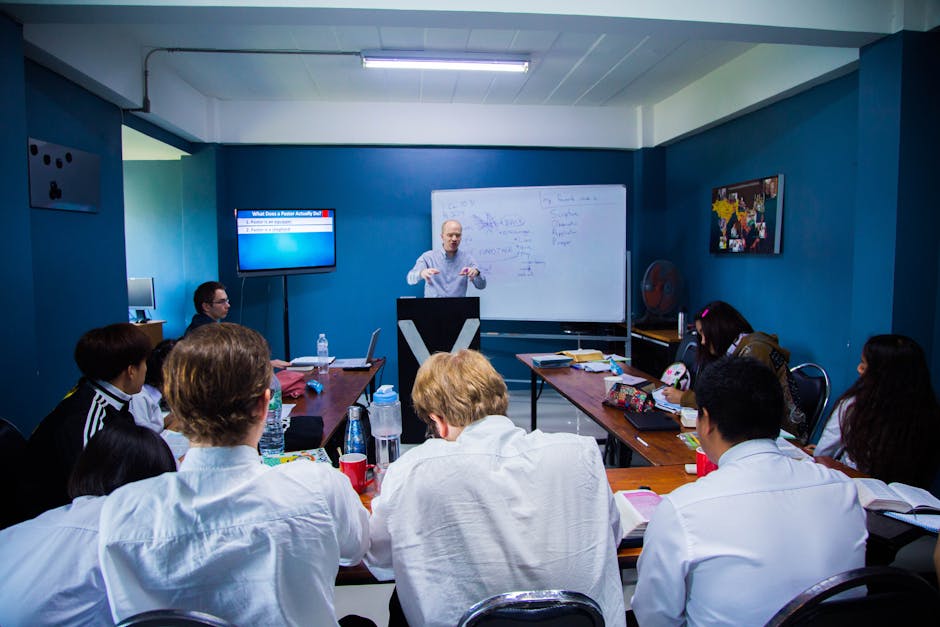 A business seminar with people attentively listening to a speaker in a modern classroom setting.